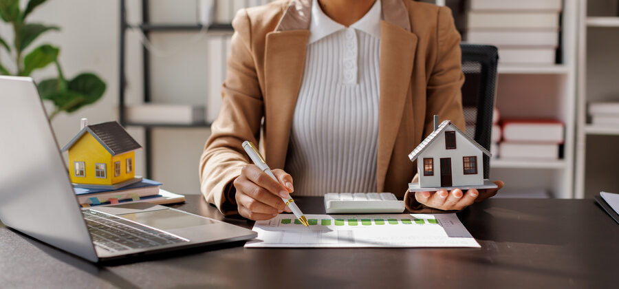 female title agent holding a house model